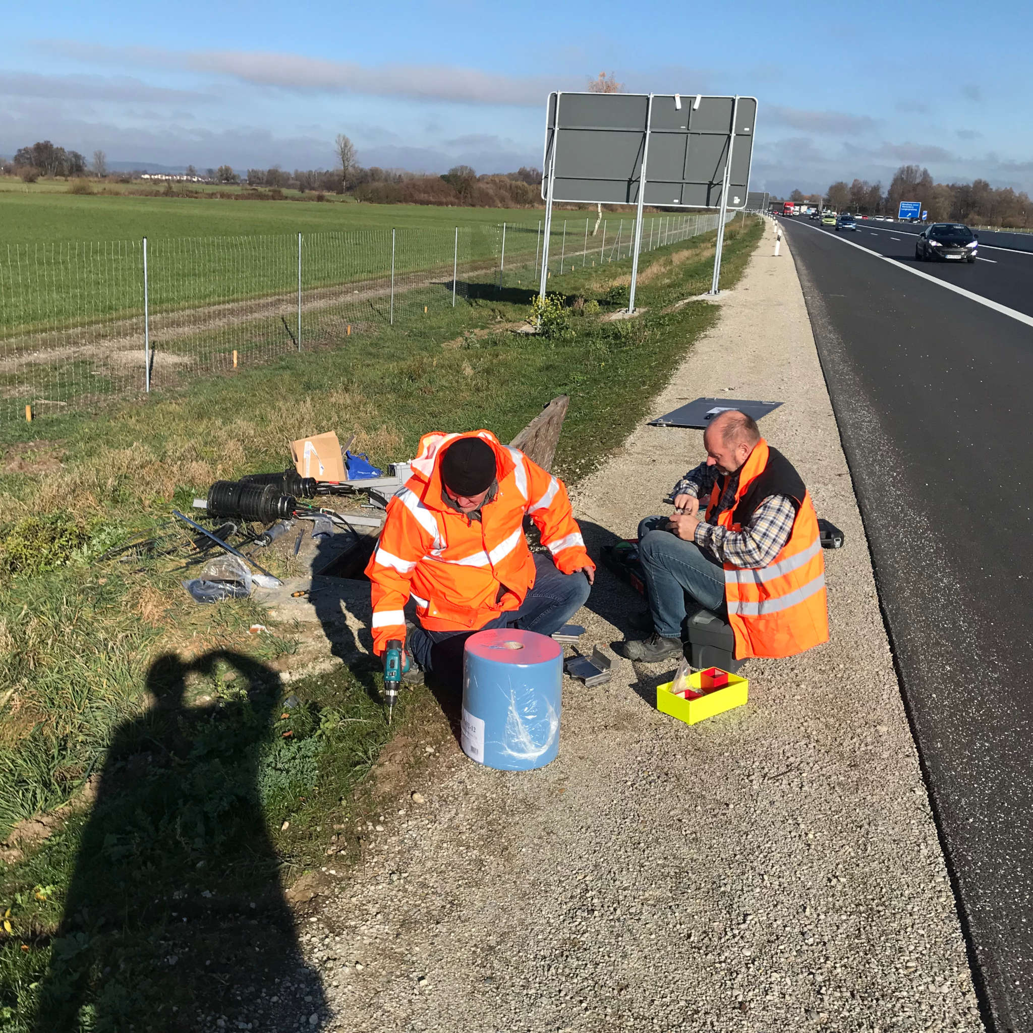 Zwei Arbeiter installieren einen Schachtsensor an einer Autobahn